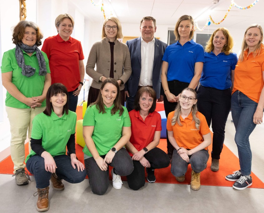 Gruppe von Pädagog:innen mit Christine Haberlander in der Mitte in einer hellen Kinderbetreuungseinrichtung.